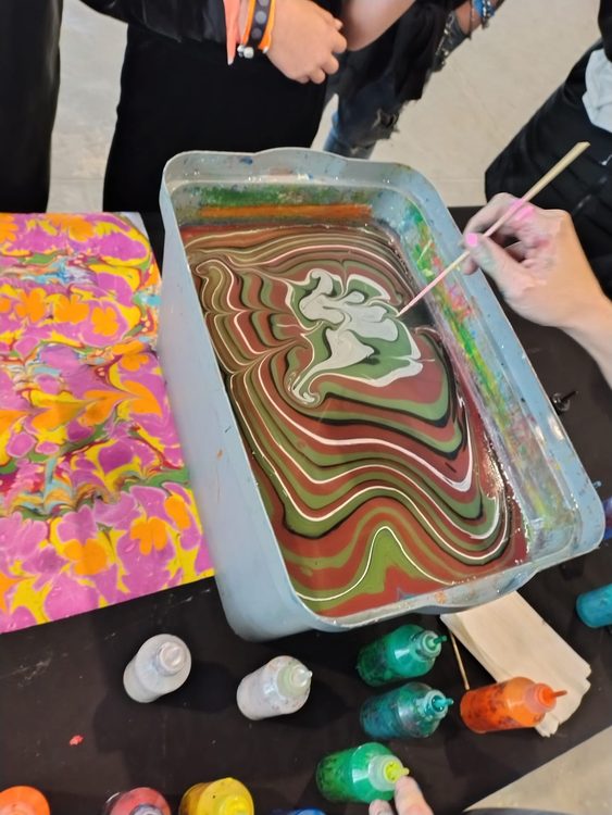 Artista preparando body marbling sobre una cubeta de agua