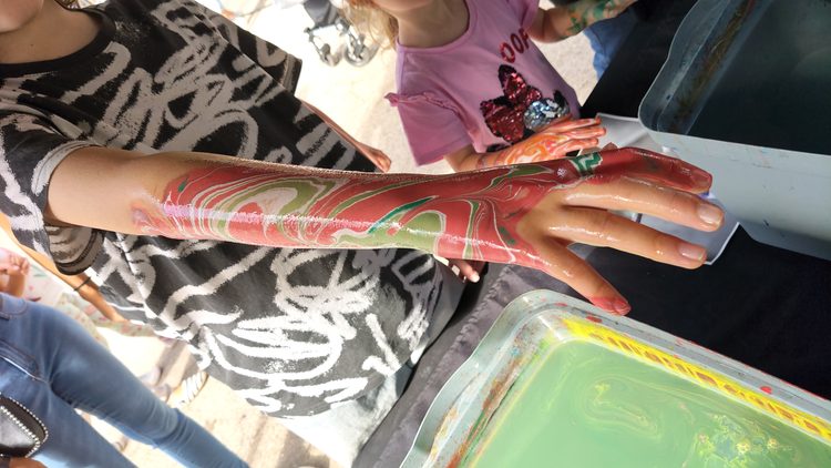 Participante sumergiendo el brazo en pintura de body marbling